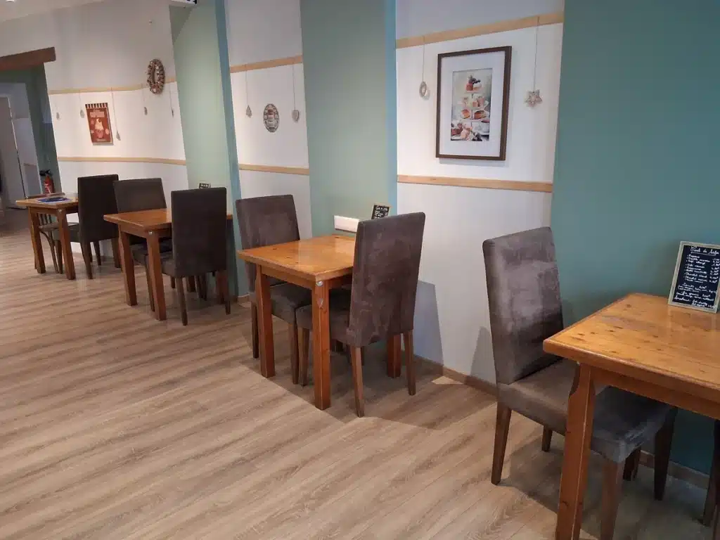 Alignement de tables en bois avec chaises rembourrées, décor chaleureux et ambiance conviviale.