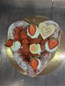 Tarte en forme de cœur garnie de fraises fraîches, volutes de chantilly, cœur en chocolat “Je t’aime” et plaque “Bonne Fête Maman”
