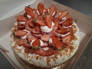 Vue plongeante d’une tarte aux fraises garnie de fraises fraîches, de crème chantilly et saupoudrée de sucre glace