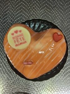 Petit entremets en forme de cœur, glaçage miroir orange, orné d’un disque “Bonne Fête Maman” et d’un petit cœur rouge