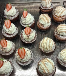 Assortiment de tartelettes individuelles : base biscuitée, généreuse volute de chantilly, certaines couronnées d’une moitié de fraise, d’autres nappées de filet de caramel et saupoudrées de sucre glace