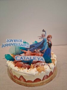Tarte décorée sur le thème “Reine des Neiges” avec figurines Elsa et Anna, morceaux de sucre colorés et inscription “Joyeux Anniversaire Cataleya”
