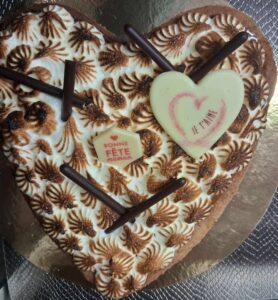 Gros cœur meringué brûlé à la torche, décoré de bâtonnets de chocolat et d’une plaque “Je t’aime”